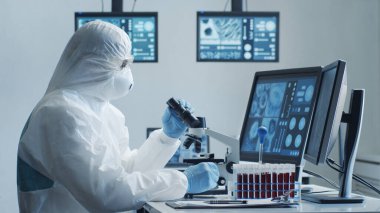 Laboratuvar ekipmanları, mikroskoplar, test tüpleri kullanarak araştırma laboratuarında çalışan koruma giysisi ve maskesi giyen bilim adamları. Coronavirus 2019-ncov tehlikesi, ilaç keşfi, bakteri bilimi ve virüs bilimi