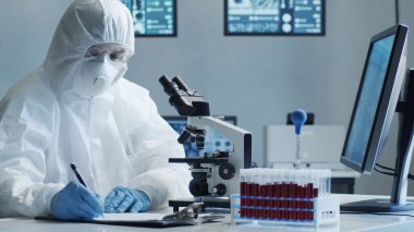 Laboratuvar ekipmanları, mikroskoplar, test tüpleri kullanarak araştırma laboratuarında çalışan koruma giysisi ve maskesi giyen bilim adamları. Coronavirus 2019-ncov tehlikesi, ilaç keşfi, bakteri bilimi ve virüs bilimi