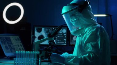 Laboratuvar ekipmanları, mikroskoplar ve test tüpleri kullanarak araştırma laboratuarında çalışan koruyucu giysi ve maskeler giyen bilim adamları. Coronavirus 2019-ncov tehlikesi, ilaç keşfi, bakteri bilimi ve virüs bilimi