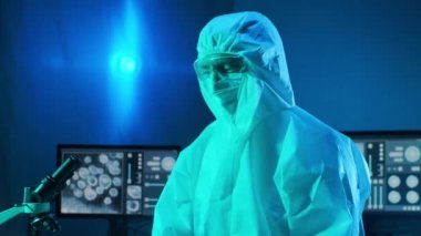 Laboratuvar ekipmanları, mikroskoplar ve test tüpleri kullanarak araştırma laboratuarında çalışan koruyucu giysi ve maskeler giyen bilim adamları. Coronavirus SARS-CoV-2 tehlikesi, ilaç keşfi, bakteri bilimi ve viroloji
