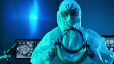 Laboratuvar ekipmanları, mikroskoplar, test tüpleri kullanarak araştırma laboratuarında çalışan koruyucu giysiler ve maskeler giyen bilim adamları. Coronavirus covid-19 tehlike, ilaç keşfi, bakteri bilimi ve virüs bilimi