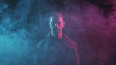 Kapüşonlu bilgisayar korsanı portresi. Neon ışıkta karanlık bir yüz. Veri hırsızlığı, internet dolandırıcılığı, darknet ve siber güvenlik kavramı.