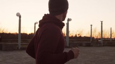 Genç adam dışarıda akşam eğitimi alıyor. Şehir günbatımı geçmişi. Spor, spor ve spor konsepti.