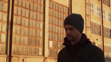 Endüstriyel binalarda yürüyen bir adamın portresi ve günbatımı. Spor ve spor konsepti.