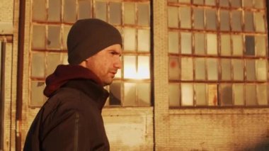 Endüstriyel binalarda yürüyen bir adamın portresi ve günbatımı. Spor ve spor konsepti.