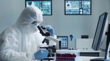 Laboratuvar ekipmanları, mikroskoplar, test tüpleri kullanarak araştırma laboratuarında çalışan koruyucu giysiler ve maskeler giyen bilim adamları. Coronavirus covid-19 tehlike, ilaç keşfi, bakteri bilimi ve virüs bilimi