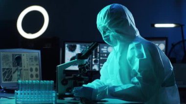 Laboratuvar ekipmanları, mikroskoplar, test tüpleri kullanarak araştırma laboratuarında çalışan koruyucu giysiler ve maskeler giyen bilim adamları. Coronavirus covid-19 tehlike, ilaç keşfi, bakteri bilimi ve virüs bilimi