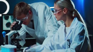 Laboratuvarda çalışan tıp bilimcileri. Doktor stajyerlere kan analizi yapmayı öğretiyor. Laboratuvar aletleri: mikroskop, test tüpleri, ekipmanlar. Koronavirüs, biyoteknoloji, bakteriyoloji, viroloji ve