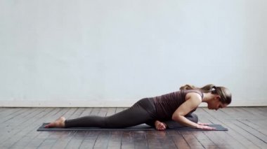 Sınıfta yoga yapan genç ve formda bir kadın. Gün ışığında esneme egzersizi. Spor, spor, sağlık hizmetleri ve yaşam tarzı kavramları.