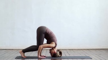 Sınıfta yoga yapan genç ve formda bir kadın. Gün ışığında esneme egzersizi. Spor, spor, sağlık hizmetleri ve yaşam tarzı kavramları.