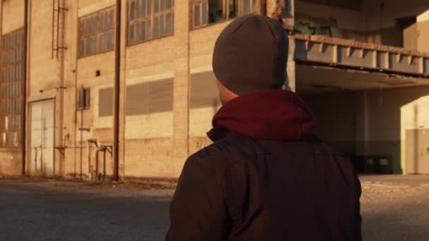 一个男人走过工业建筑和日落背景的画像 健康与体育概念 — 图库视频影像