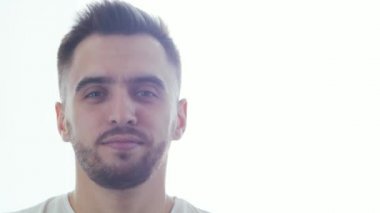 Pencere arkasında etkileyici bir genç adam. Gülümseyen yakışıklı birinin ev resmi. Doğal gün ışığı.