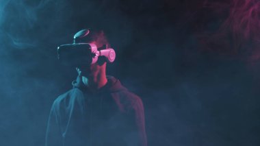 Sanal gerçeklik kaskı takmış bir adamın portresi. VR gözlüklü karanlık yüz. İnternet, darknet, oyun ve siber simülasyon kavramı.