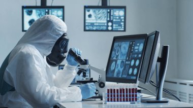 Laboratuvar ekipmanları, mikroskoplar ve test tüpleri kullanarak araştırma laboratuarında çalışan koruyucu giysi ve maskeler giyen bilim adamları. Coronavirus 2019-ncov tehlikesi, ilaç keşfi, bakteri bilimi ve virüs bilimi