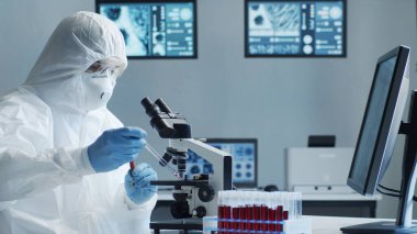 Laboratuvar ekipmanları, mikroskoplar ve test tüpleri kullanarak araştırma laboratuarında çalışan koruyucu giysi ve maskeler giyen bilim adamları. Coronavirus 2019-ncov tehlikesi, ilaç keşfi, bakteri bilimi ve virüs bilimi