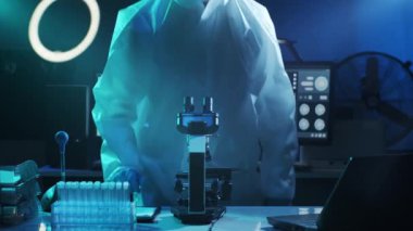 Laboratuvar ekipmanları, mikroskoplar ve test tüpleri kullanarak araştırma laboratuarında çalışan koruyucu giysi ve maskeler giyen bilim adamları. Coronavirus 2019-ncov tehlikesi, ilaç keşfi, bakteri bilimi ve virüs bilimi