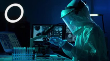 Laboratuvar ekipmanları, mikroskoplar, test tüpleri kullanarak araştırma laboratuarında çalışan koruyucu giysiler ve maskeler giyen bilim adamları. Coronavirus covid-19 tehlike, ilaç keşfi, bakteri bilimi ve virüs bilimi