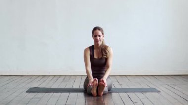 Sınıfta yoga yapan genç ve formda bir kadın. Gün ışığında esneme egzersizi. Spor, spor, sağlık hizmetleri ve yaşam tarzı kavramları.