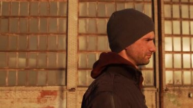 Endüstriyel binalarda yürüyen bir adamın portresi ve günbatımı. Spor ve spor konsepti.