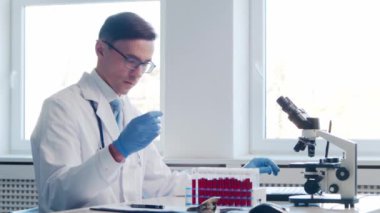 Laboratuvarda çalışan bir bilim adamı. Doktor mikrobiyoloji araştırması yapıyor. Laboratuvar aletleri: mikroskop, test tüpleri, ekipmanlar. Biyoteknoloji, kimya, bakteriyoloji, viroloji, DNA ve sağlık hizmetleri kavramı.