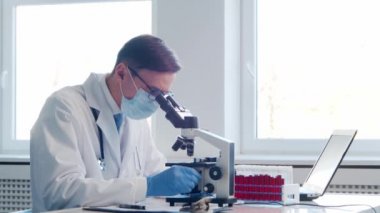Laboratuvarda çalışan bir bilim adamı. Doktor mikrobiyoloji araştırması yapıyor. Laboratuvar aletleri: mikroskop, test tüpleri, ekipmanlar. Biyoteknoloji, kimya, bakteriyoloji, viroloji, DNA ve sağlık hizmetleri kavramı.