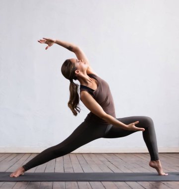 Sınıfta yoga yapan genç ve formda bir kadın. Gün ışığında esneme egzersizi. Spor, spor, sağlık hizmetleri ve yaşam tarzı kavramları.
