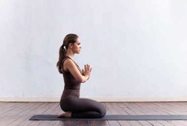 Sınıfta yoga yapan genç ve formda bir kadın. Gün ışığında esneme egzersizi. Spor, spor, sağlık hizmetleri ve yaşam tarzı kavramları.