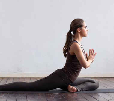 Sınıfta yoga yapan genç ve formda bir kadın. Gün ışığında esneme egzersizi. Spor, spor, sağlık hizmetleri ve yaşam tarzı kavramları.