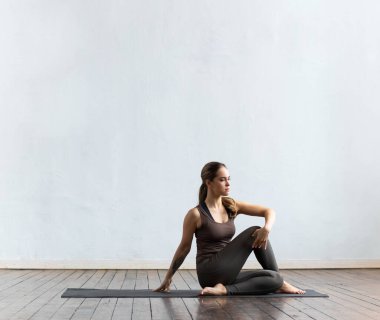 Sınıfta yoga yapan genç ve formda bir kadın. Gün ışığında esneme egzersizi. Spor, spor, sağlık hizmetleri ve yaşam tarzı kavramları.