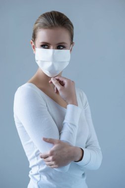 Tıbbi maskeli genç ve doğal bir kadının portresi. Güzel gün ışığı. Salgın, koronavirüs, covid-19 ve koruma konsepti..