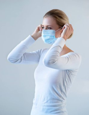 Tıbbi maskeli genç ve doğal bir kadının portresi. Güzel gün ışığı. Salgın, koronavirüs, covid-19 ve koruma konsepti..