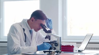 Laboratuvarda çalışan bir bilim adamı. Doktor mikrobiyoloji araştırması yapıyor. Laboratuvar aletleri: mikroskop, test tüpleri, ekipmanlar. Biyoteknoloji, kimya, bakteriyoloji, viroloji, DNA ve sağlık hizmetleri kavramı.