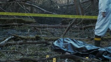 Dedektifler suç mahallinde delil topluyor. Adli tıp uzmanları uzmanlık yapıyor. Ormanda polis memurları ve soruşturma.