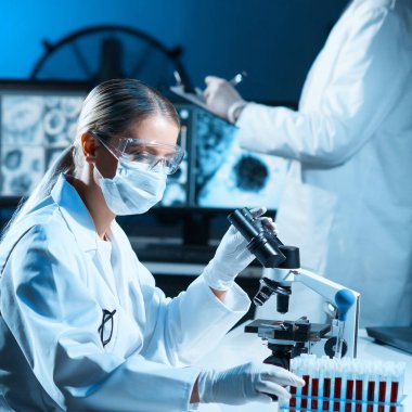 Modern laboratuvarda çalışan bilim adamları. Doktor mikrobiyoloji araştırması yapıyor. Laboratuvar aletleri: mikroskop, test tüpleri, ekipmanlar. Bakteriyoloji, viroloji ve sağlık hizmetleri kavramı.