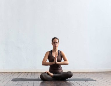 Sınıfta yoga yapan genç ve formda bir kadın. Gün ışığında esneme egzersizi. Spor, spor, sağlık hizmetleri ve yaşam tarzı kavramları.
