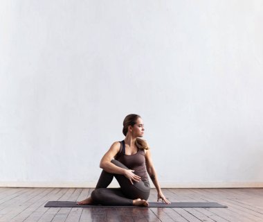 Sınıfta yoga yapan genç ve formda bir kadın. Gün ışığında esneme egzersizi. Spor, spor, sağlık hizmetleri ve yaşam tarzı kavramları.
