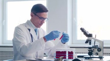 Laboratuvarda çalışan bir bilim adamı. Doktor mikrobiyoloji araştırması yapıyor. Laboratuvar aletleri: mikroskop, test tüpleri, ekipmanlar. Biyoteknoloji, kimya, bakteriyoloji, viroloji, DNA ve sağlık hizmetleri kavramı.