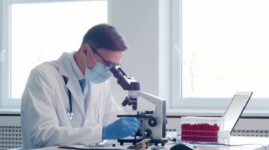 Laboratuvarda çalışan bir bilim adamı. Doktor mikrobiyoloji araştırması yapıyor. Laboratuvar aletleri: mikroskop, test tüpleri, ekipmanlar. Biyoteknoloji, kimya, bakteriyoloji, viroloji, DNA ve sağlık hizmetleri kavramı.