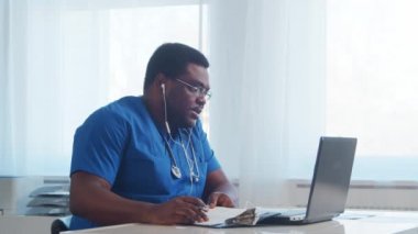 Profesyonel Afro-Amerikan tıp doktoru hastane ofisinde bilgisayar teknolojisi kullanıyor. Çevrimiçi danışma, tıp ve sağlık konsepti.