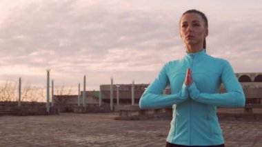 Genç, güzel ve sportif bir kadın akşam yoga eğitimi alıyor. Şehir günbatımı geçmişi. Spor ve spor konsepti.