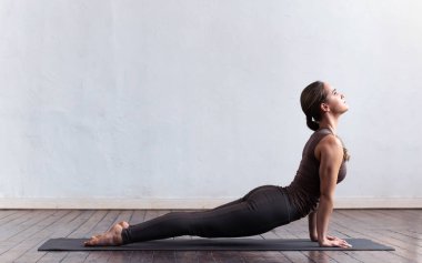 Sınıfta yoga yapan genç ve formda bir kadın. Gün ışığında esneme egzersizi. Spor, spor, sağlık hizmetleri ve yaşam tarzı kavramları.
