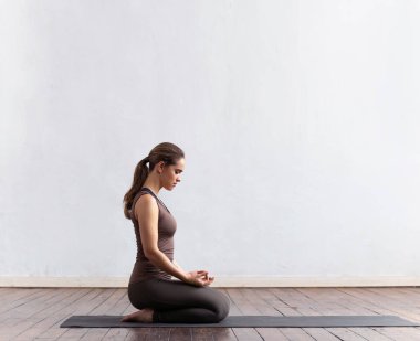 Sınıfta yoga yapan genç ve formda bir kadın. Gün ışığında esneme egzersizi. Spor, spor, sağlık hizmetleri ve yaşam tarzı kavramları.