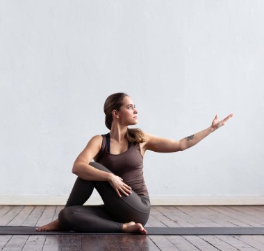 Sınıfta yoga yapan genç ve formda bir kadın. Gün ışığında esneme egzersizi. Spor, spor, sağlık hizmetleri ve yaşam tarzı kavramları.