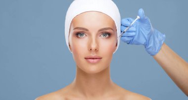 Genç bir kadının güzel yüzüne iğne yapan bir doktor. Estetik ameliyat, cilt gerdirme ve estetik tıp konsepti.
