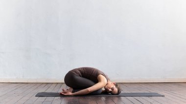 Sınıfta yoga yapan genç ve formda bir kadın. Gün ışığında esneme egzersizi. Spor, spor, sağlık hizmetleri ve yaşam tarzı kavramları.