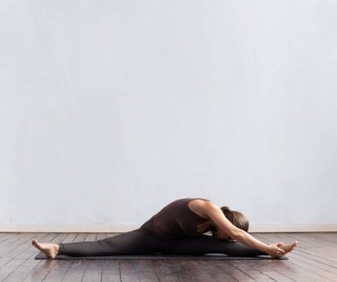 Sınıfta yoga yapan genç ve formda bir kadın. Gün ışığında esneme egzersizi. Spor, spor, sağlık hizmetleri ve yaşam tarzı kavramları.