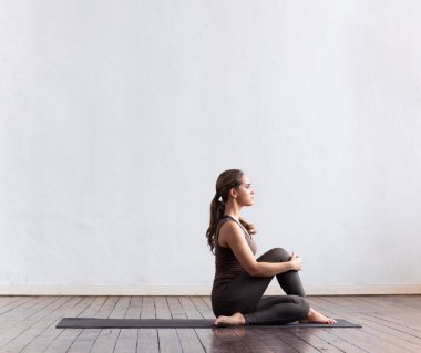 Sınıfta yoga yapan genç ve formda bir kadın. Gün ışığında esneme egzersizi. Spor, spor, sağlık hizmetleri ve yaşam tarzı kavramları.