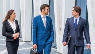 Takım çalışması ve iş konsepti. Resmi olarak kendine güvenen işadamları ofis binası önünde bankacılık ve finans piyasaları hakkında konuşuyorlar. İş adamları ve iş kadını.