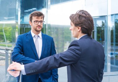 Takım çalışması ve iş konsepti. Resmi olarak kendine güvenen işadamları ofis binası önünde bankacılık ve finans piyasaları hakkında konuşuyorlar..