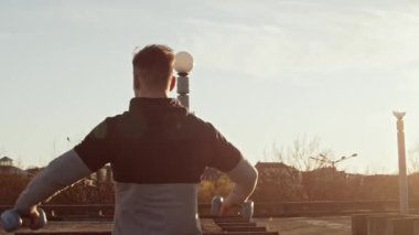 Genç ve zinde bir adam dışarıda akşam antrenmanı yapıyor. Şehir günbatımı geçmişi. Spor ve spor kavramları.